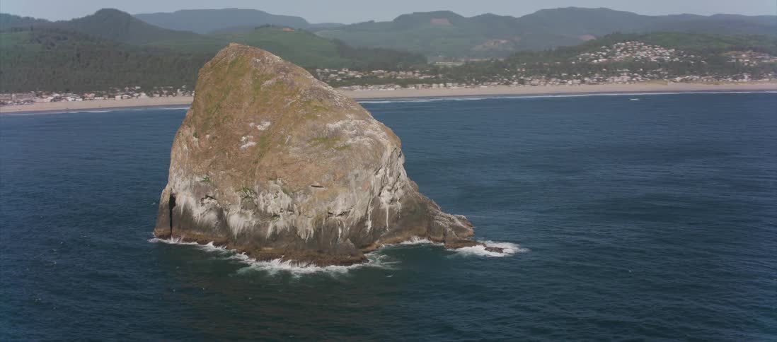 A large rock formation surrounded by ocean water