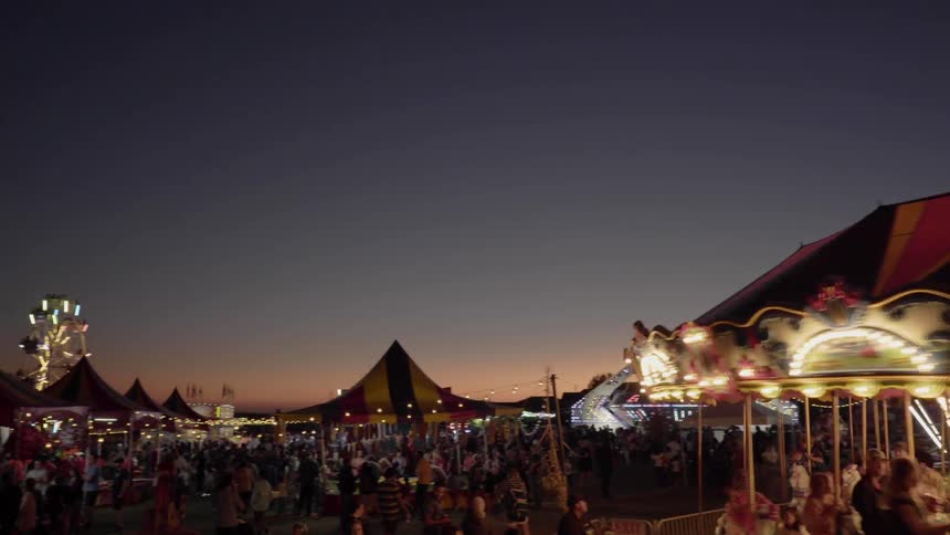 People ride a merry go round and play games at a fair at night