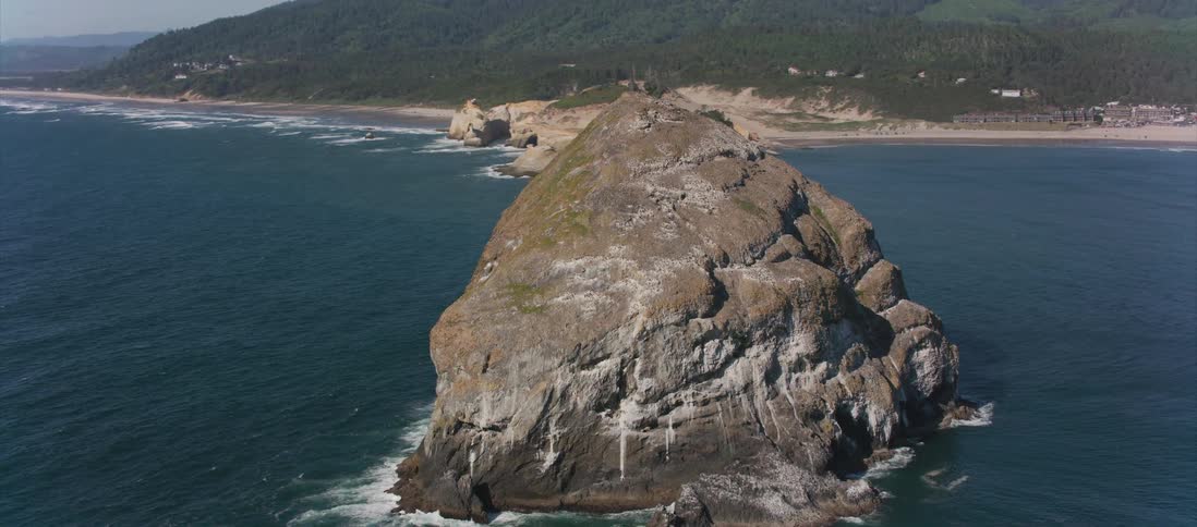 An islet sits in the ocean not far from the shore
