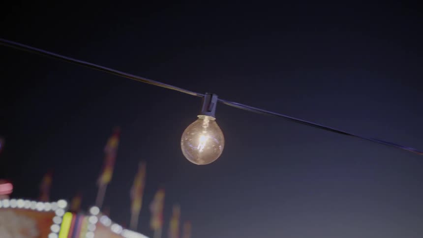 A string of lights across a carnival grounds at night