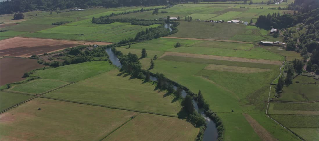 Aerial view of a small river flowing through farmland