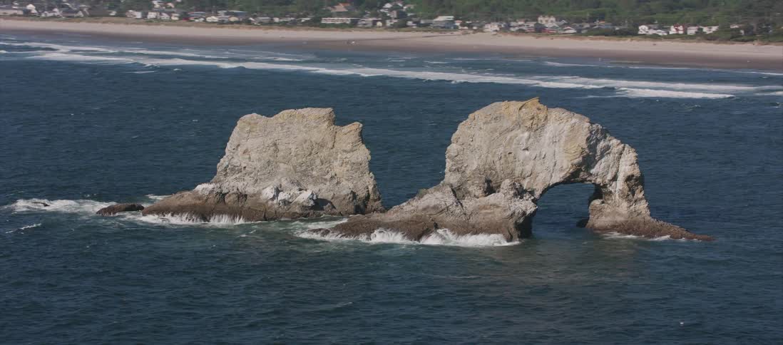 View of two big rocks in the middle of sea on a sunny day