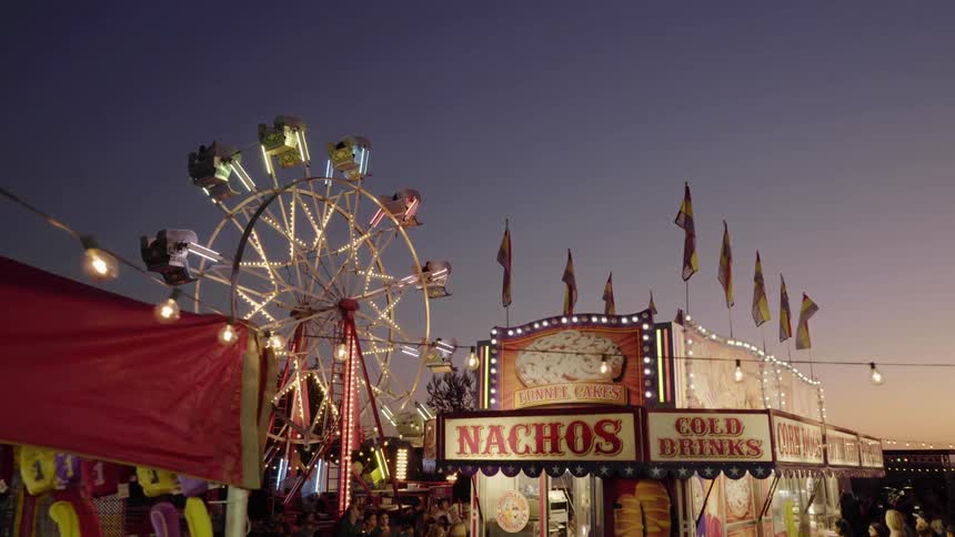 Ferris wheel spins in the theme park at dusk