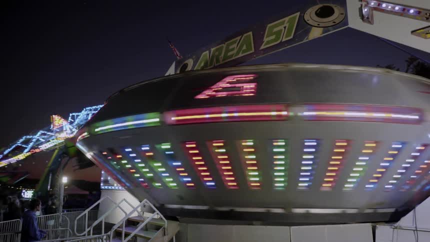 People are waiting in line for a fast spinning carnival ride
