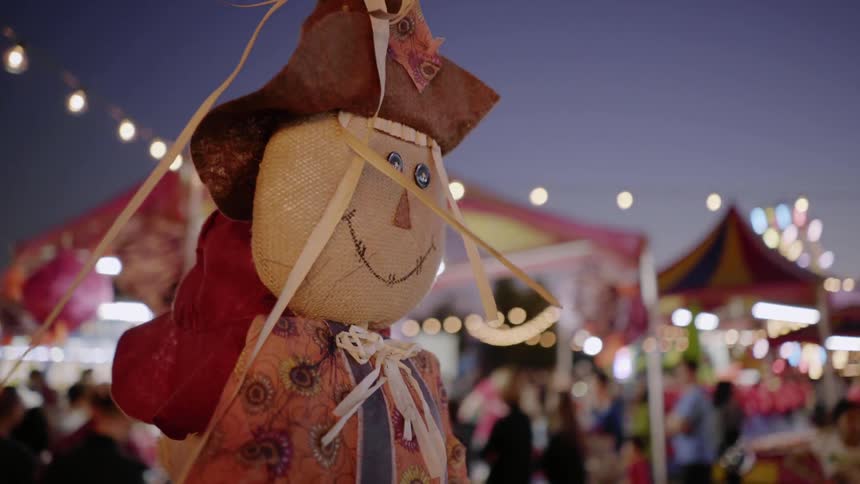 A scarecrow stands in the middle of the fall carnival