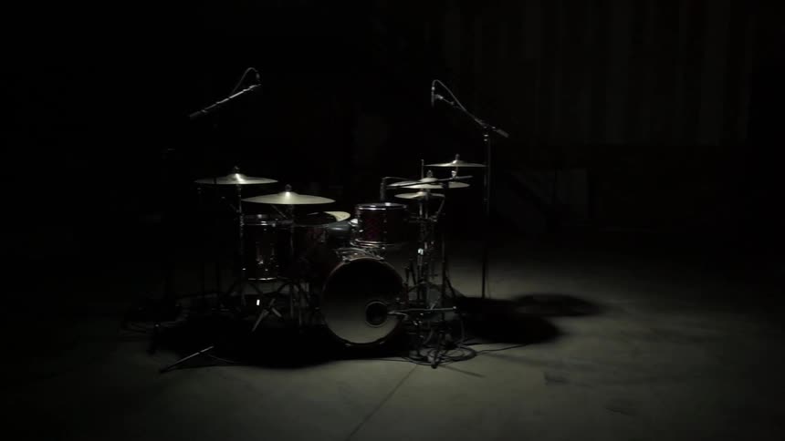 The drums sit in the middle of the dark stage