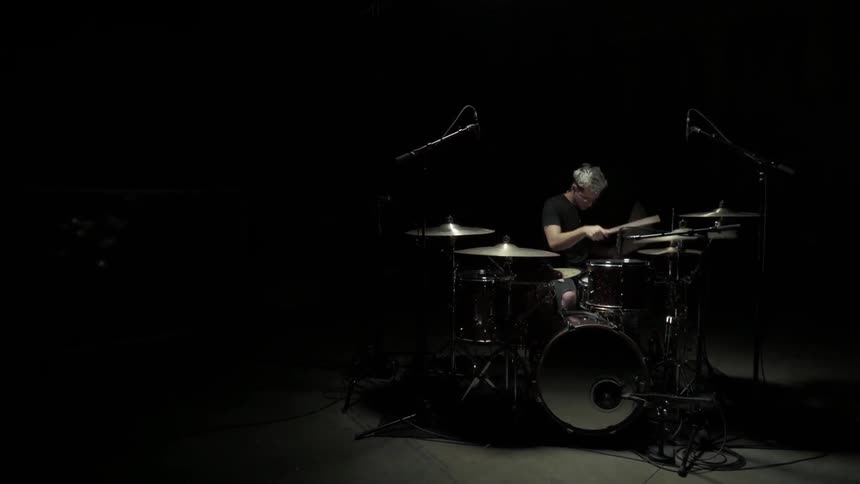 Man sitting in a dark room playing drums