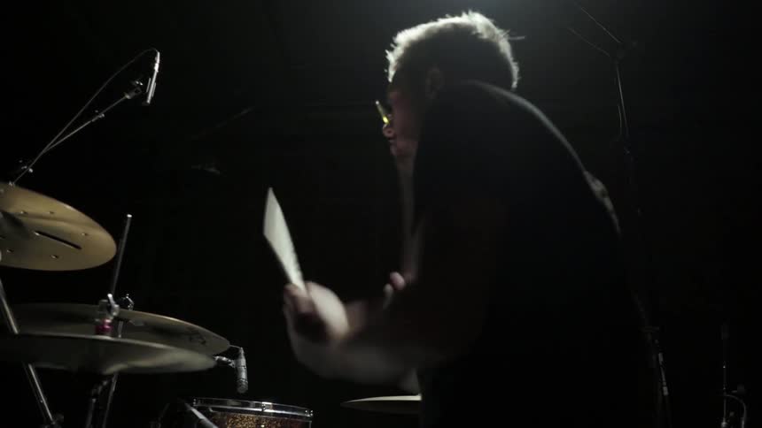 A man is playing a full set of drums very quickly as if to a rock and roll song
