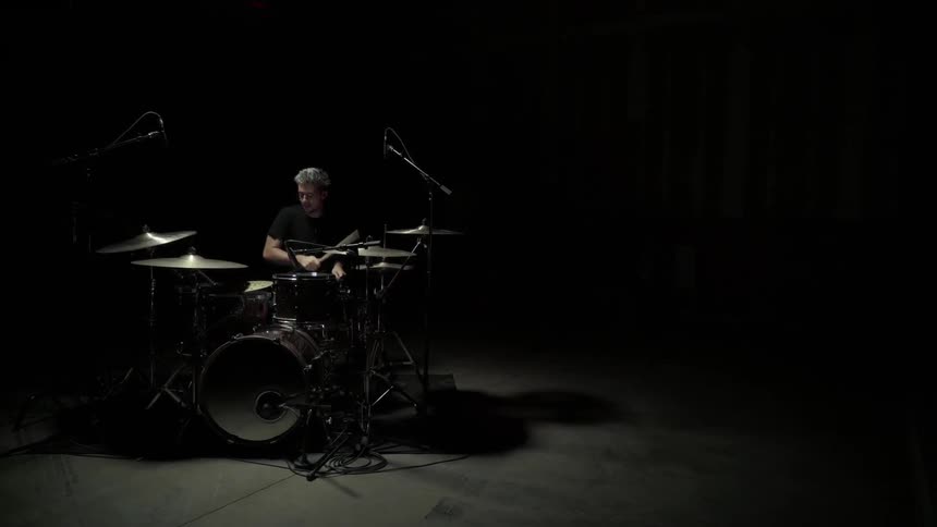 A drummer plays in the darkness