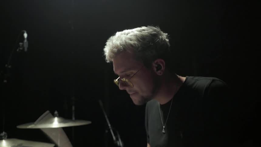 A young white man plays a drum set