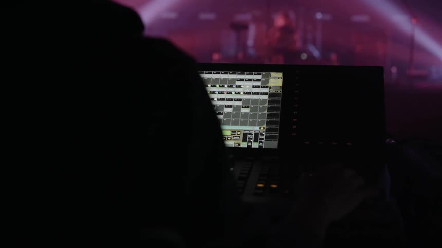 A person is using a panel to control the stage for a band