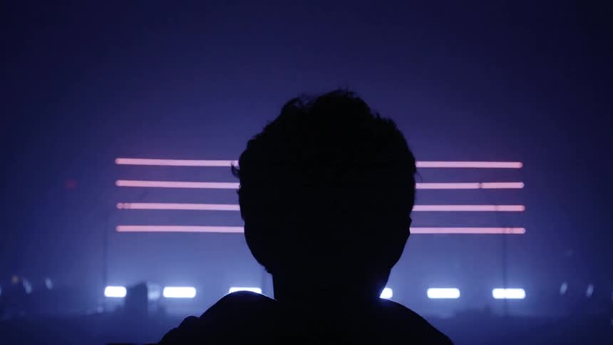 A man watches bright lights appear on a stage