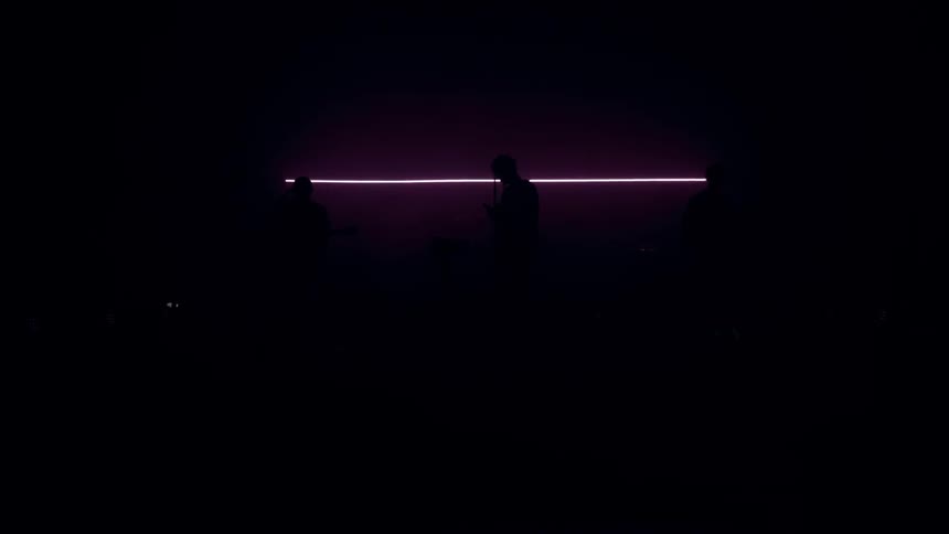 A purple light outlines the silhouettes of three people
