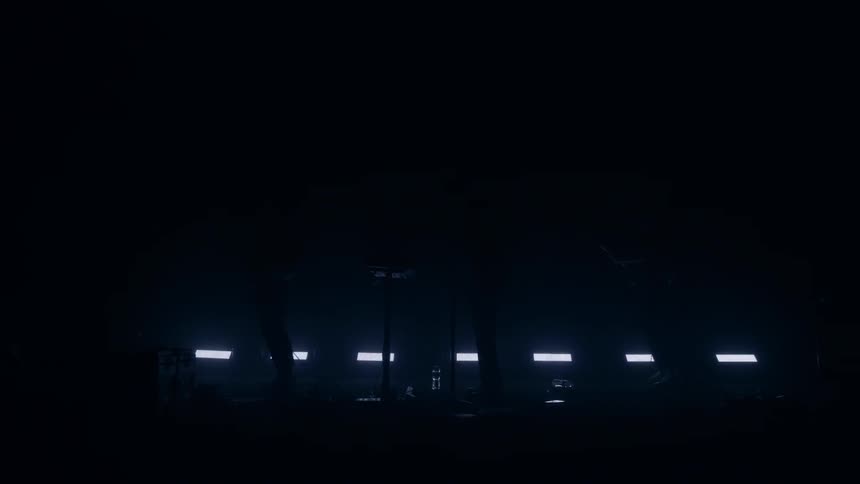 Three musicians on a dark stage with lights flashing