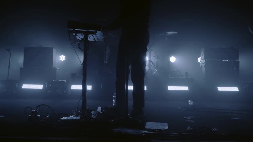 Musicians perform on a dark stage lit only from behind