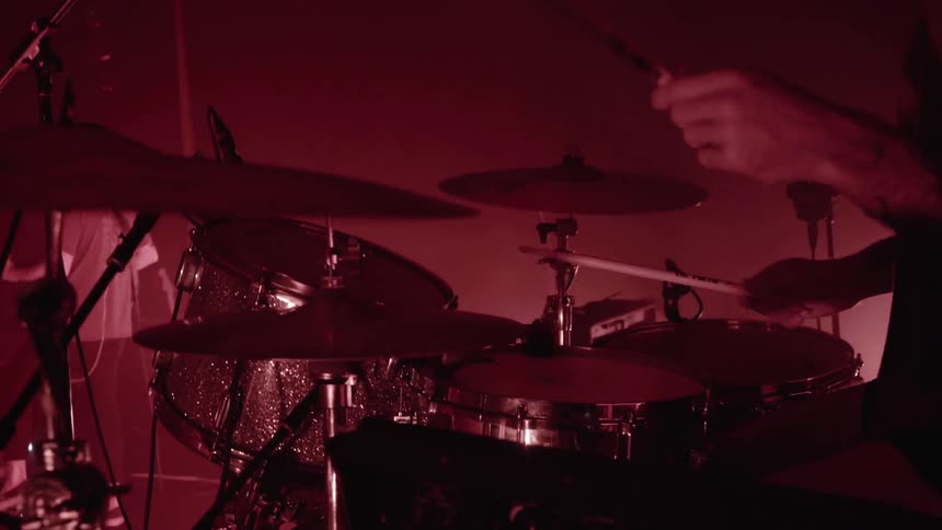 A man is playing drums with a band on stage