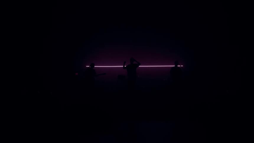 Dancers silhouettes move before a thin purple line