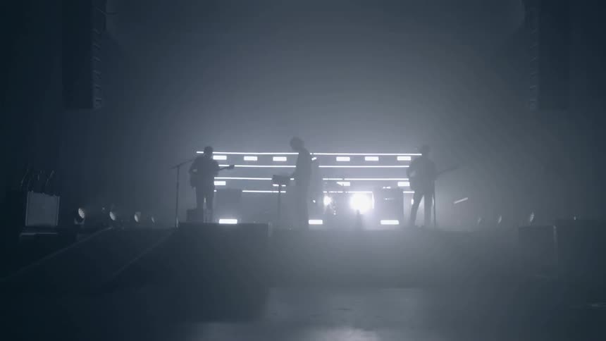 Music band perform on dark stage with lights at back