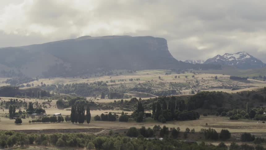 The camera looks across a valley towards mountains