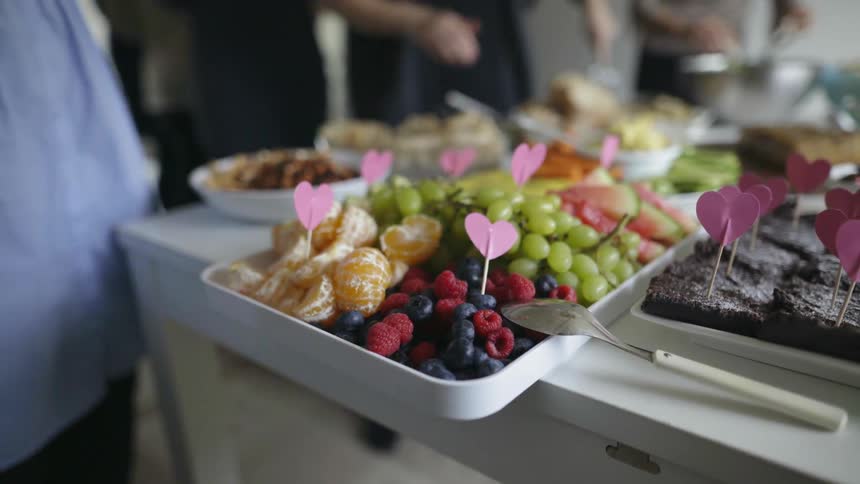 People grab food from a buffet on a table