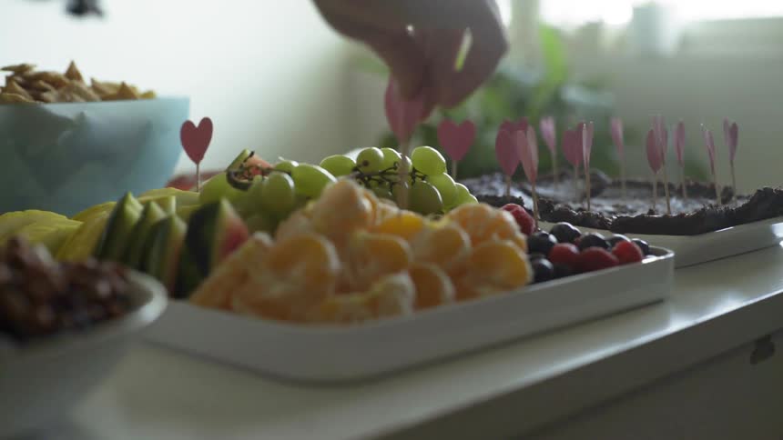 A woman puts heart shaped tooth pics in platters of food