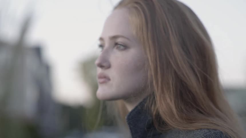 A woman stands outside on a windy day