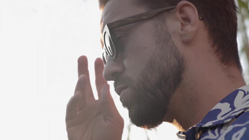 A white man puts on a pair of sunglasses