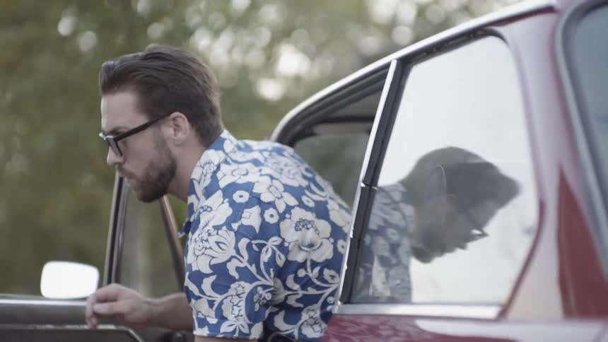 A man with shades coming out of a red car