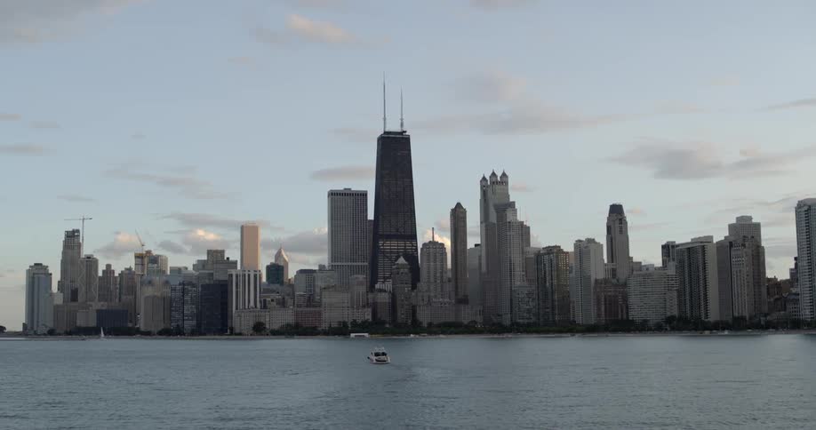 A single boat sails in the water in front of Chicago's skyline
