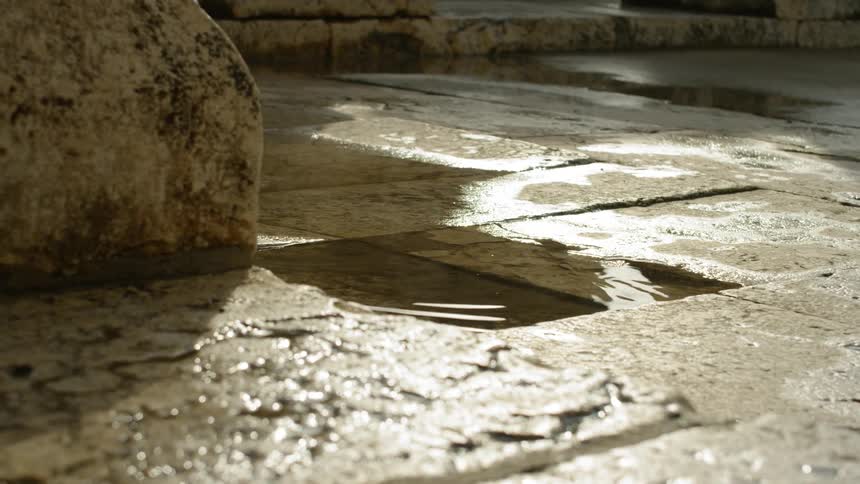 A drop falls in a puddle on the stone