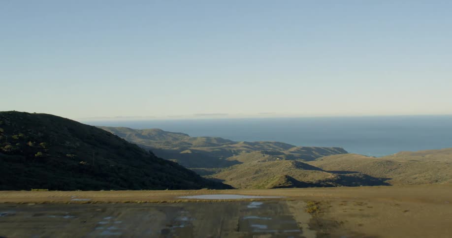 An airstrip leading into a drop off into the valley of a hilly countryside
