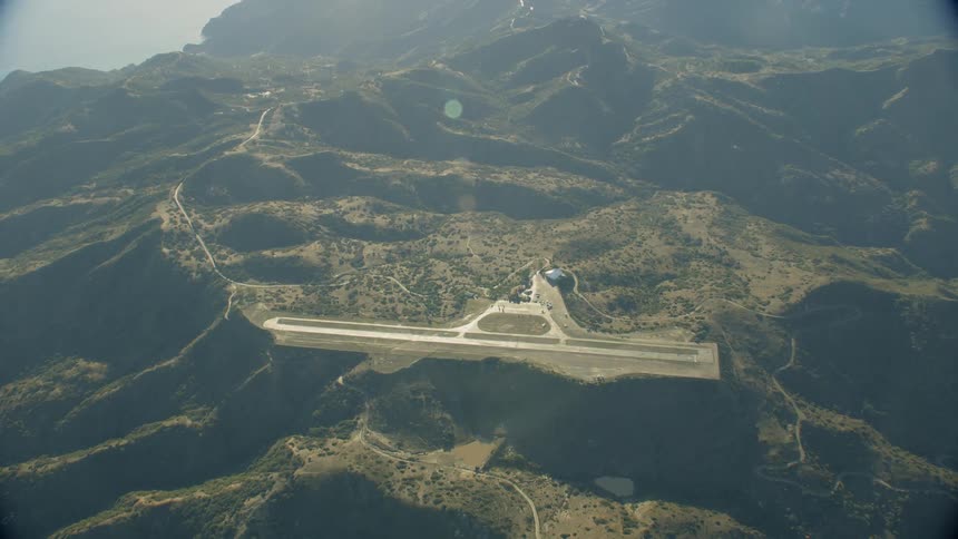 An airplane landing strip is seen overhead on a mountainside at dawn