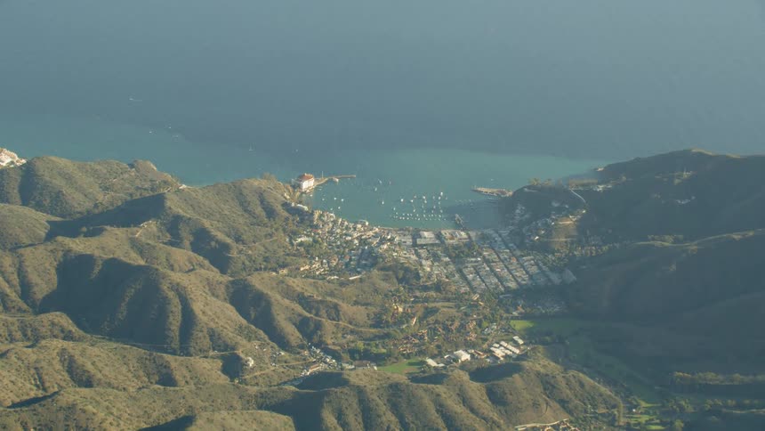 A coastal settlement viewed from the air is surrounded by mountains