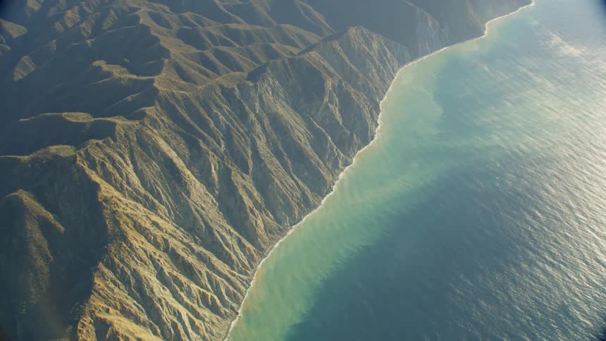 Towering mountains rise up from the blue ocean
