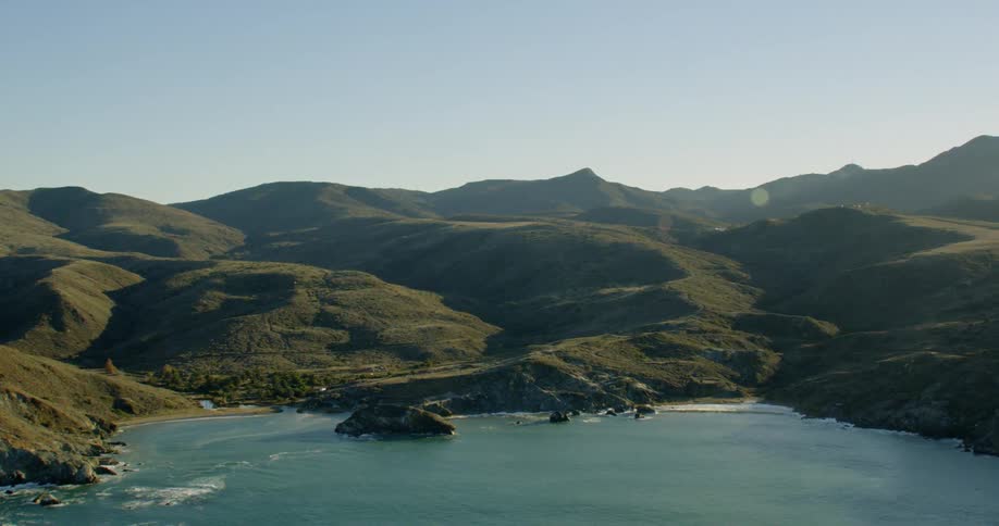Green hills and crags border ocean