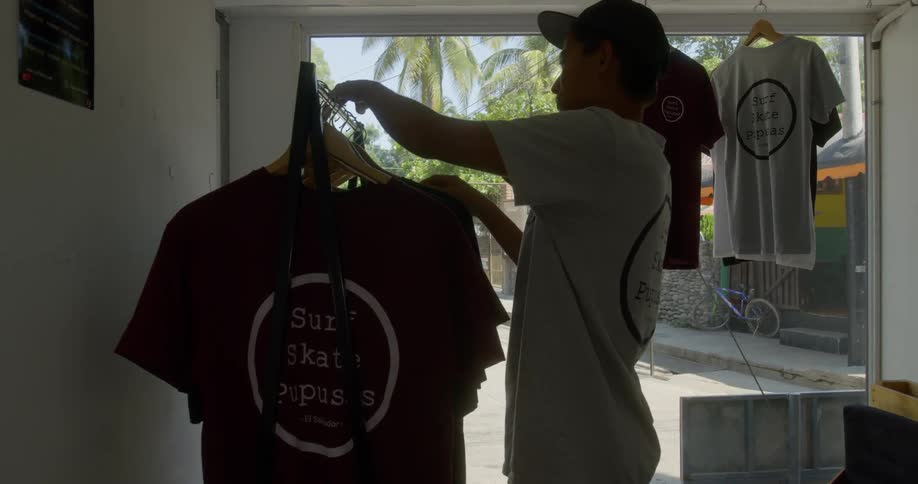A man hangs a shirt on a store clothing rack