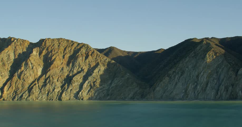 A steep and rocky coast under a clear blue sky