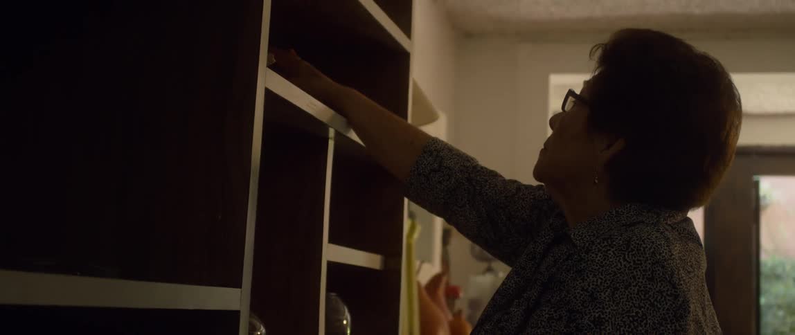 A man reaches for something in a shelf in the cabinet in a home at day