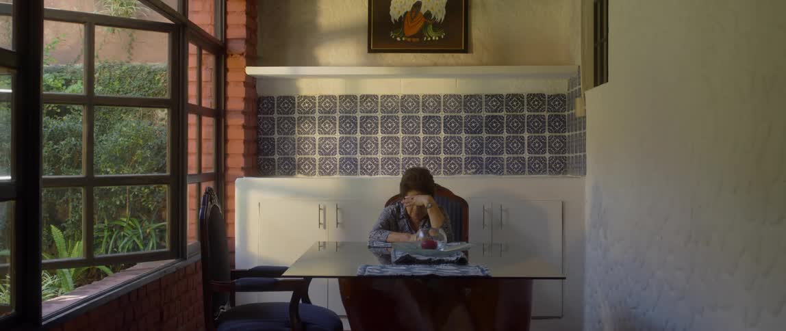 A stressed out asian woman lowers her head as she deals with the frustration of the situation while sitting at the table