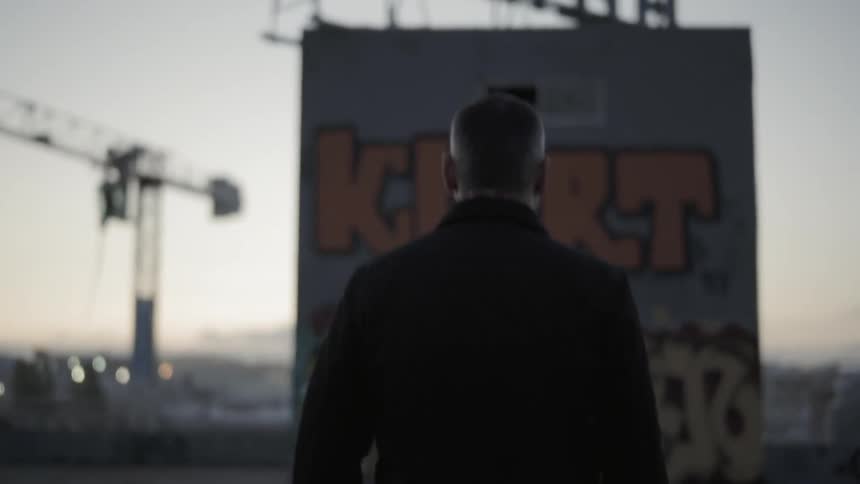 A man with jeans and a jacket walking on a rooftop