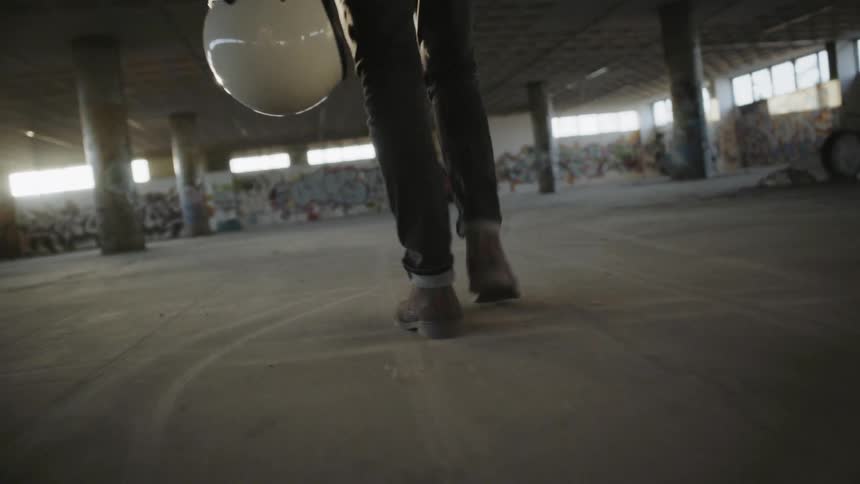 A man walks into a building carrying a helmet