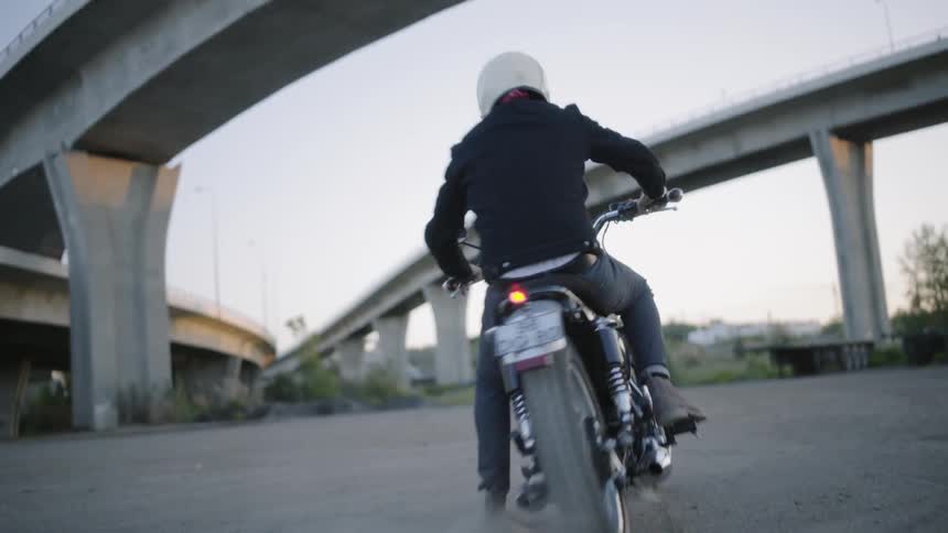 A man rides off on a motorcycle