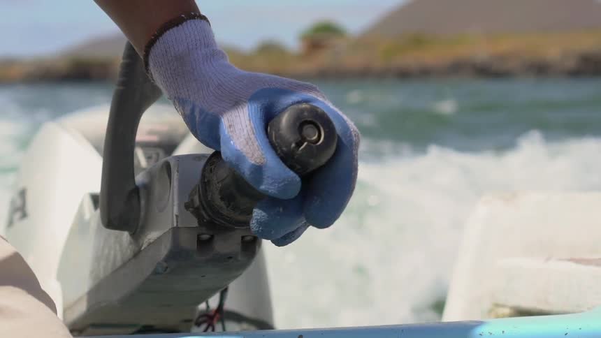 A white person throttles a boat engine
