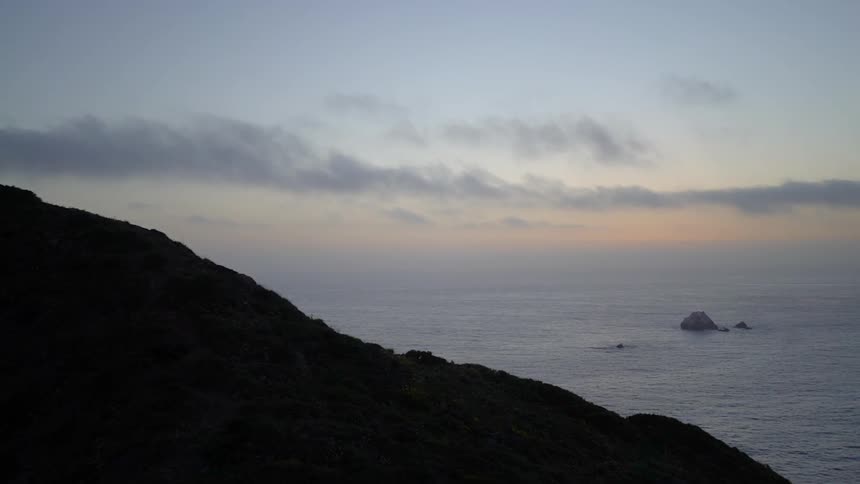 A rocky cliff overlooking the ocean and sky