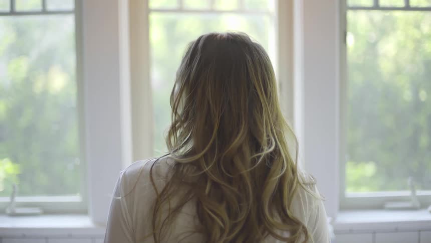 Woman standing on a room looking out a window