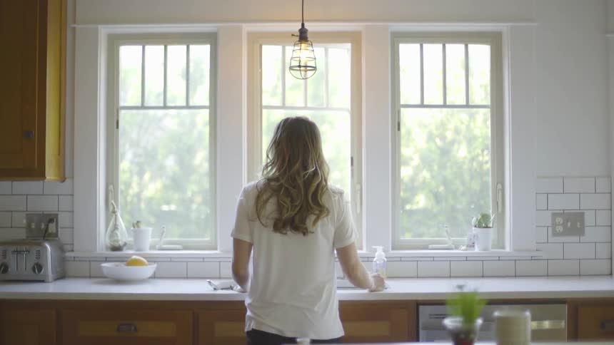 Woman stands looking out kitchen window