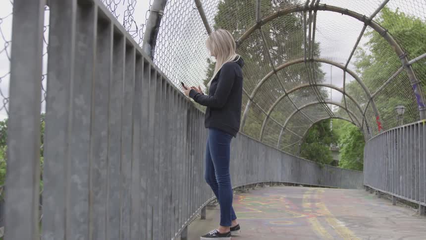 Woman stands on wire covered bridge