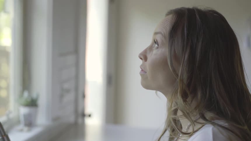 A woman contemplates while standing in a room