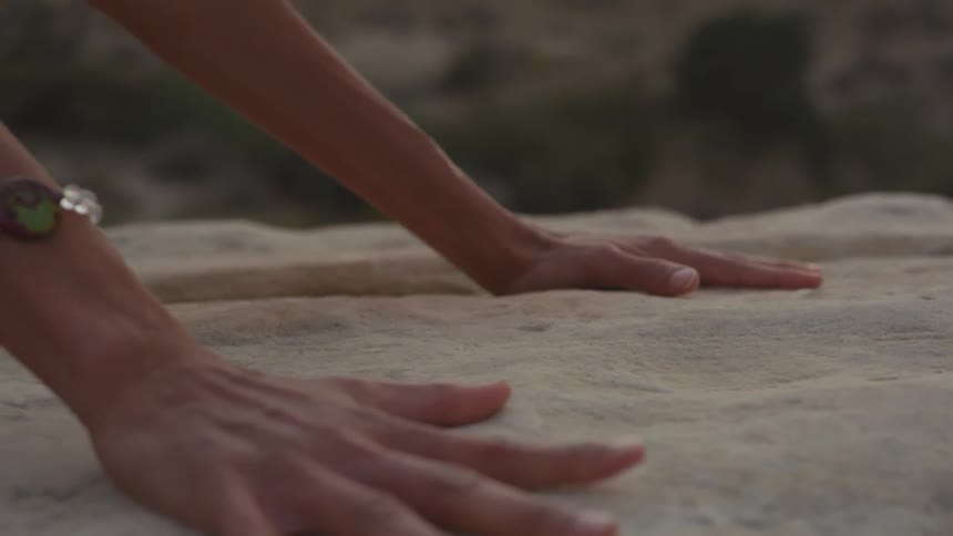 A person has their hands on a white rock