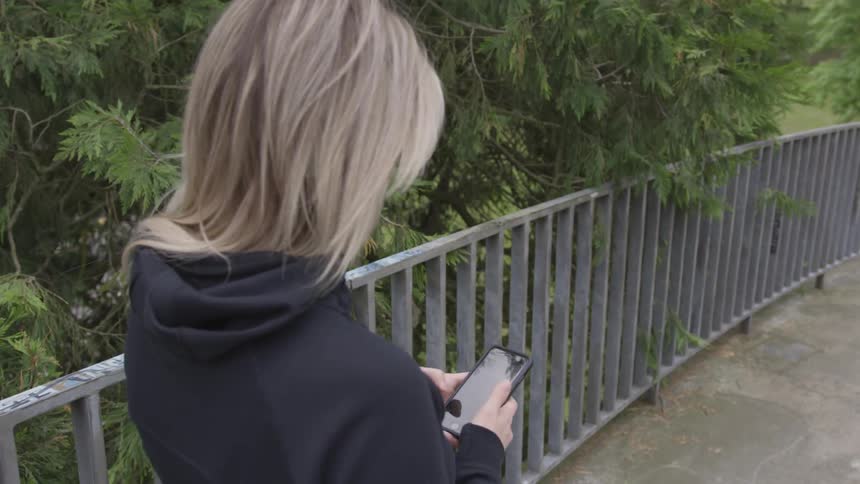 A young girl looks at her phone while walking along a pathway